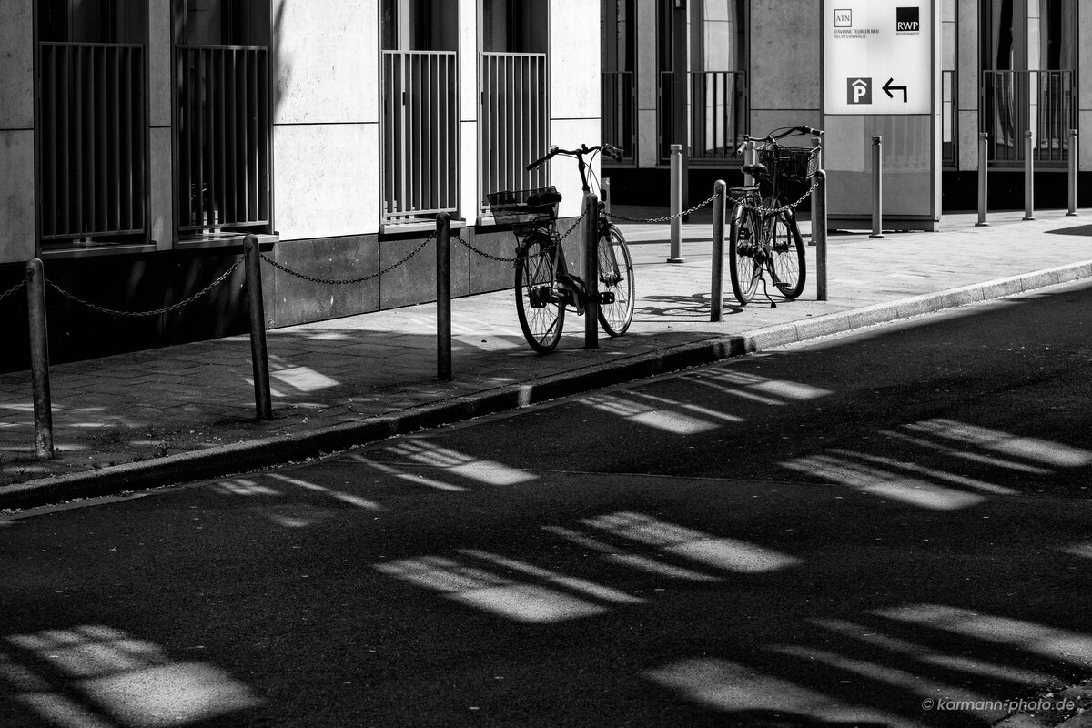 Schwarz-weiß Foto von Fahrräder und Schatten in städtischer Umgebung