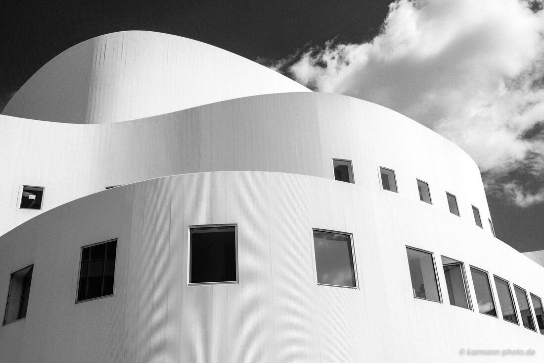 Moderne Architektur eines geschwungenen weißen Gebäudes mit Wolkenhimmel